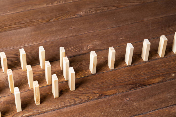 Rows of dominoes standing on wooden table. Business assistance and management concept with wooden blocks. Domino effect presentation. Chain reaction and connection. Business strategy presentation - Fotó, kép
