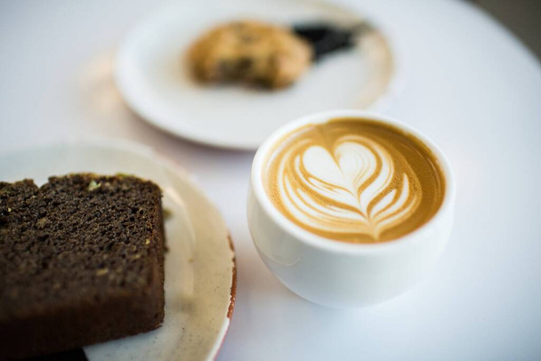 A selective focus shot of a delicious coffee on a white cup with a heart design - Foto, immagini