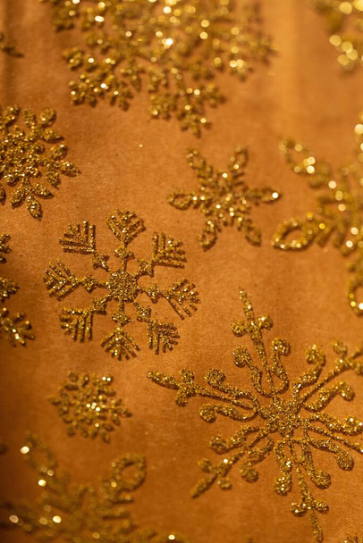 A vertical closeup shot of a golden textile with snowflake patterns - Foto, immagini