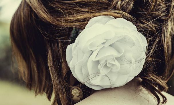 A white rose attached to a woman's hair - Фото, зображення
