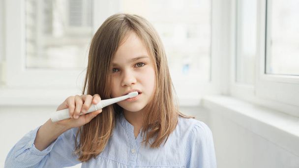 teen girl cleans teeth electric toothbrush - Фото, изображение