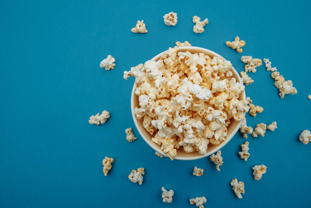 Popcorn in a bowl on blue background, top view - Fotoğraf, Görsel