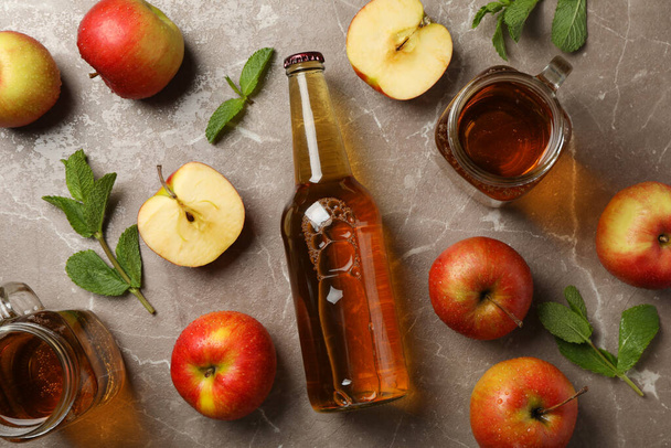 Samenstelling met cider en appels op grijze ondergrond - Foto, afbeelding