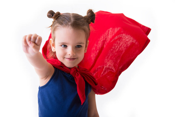 Adorable little girl flying like a superhero in blue t-shirt and red mantle. Super girl. The new generation saves the world. Good triumphs over evil. Funny kid portrait - Photo, Image