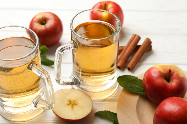 Composition with cider, cinnamon and apples on white wooden background - Photo, Image