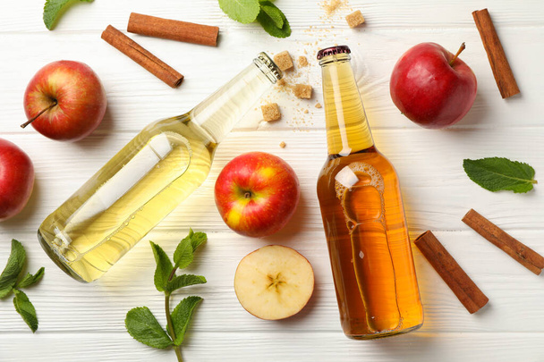 Samenstelling met cider, kaneel en appels op witte houten ondergrond - Foto, afbeelding