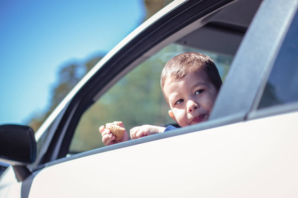 Küçük çocuk arabanın camından dışarı bakıyor. - Fotoğraf, Görsel
