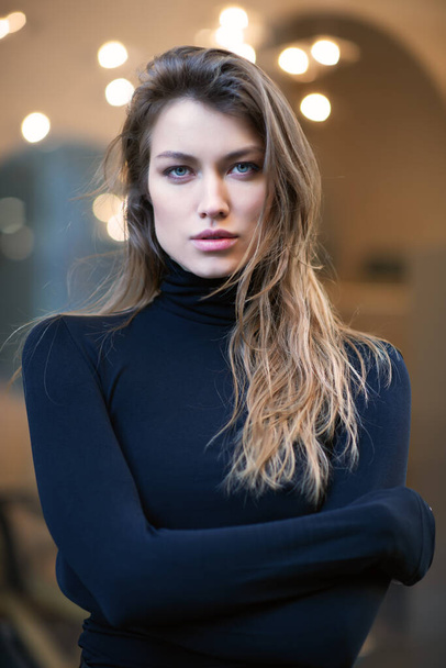 Young caucasian fashionable woman dressed in black clothes posing outdoor over Christmas Eve lights. Beautiful caucasian girl in Milan, Italy. Street fashion, winter holidays - Foto, Bild