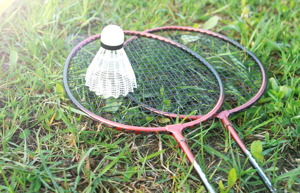  badminton rackets and shuttlecock are lying on the grass. outdoor recreation concept. - Photo, Image