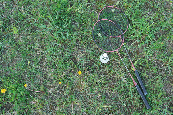Badmintonschläger und Federball liegen auf dem Rasen. Outdoor-Freizeitkonzept. mit Platz für Ihren Text - Foto, Bild