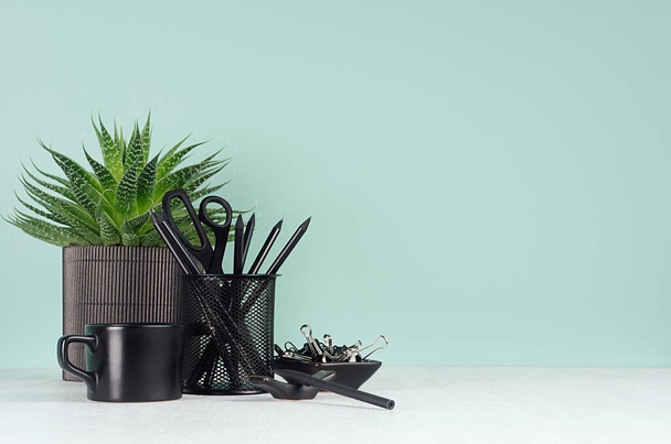 Spring home office for business and study with black stationery, coffee cup, aloe plant, pencils in light green mint menthe interior on white wood desk, copy space. - Foto, Bild