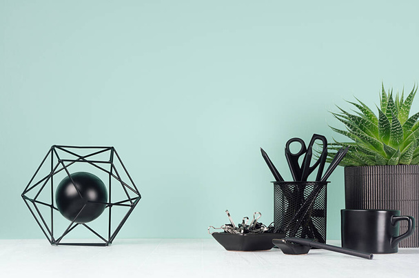Home interior - workplace with black stationery, green house plant, coffee cup, aloe plant, abstract atom model in green mint menthe color on white wood desk, copy space. - Photo, image