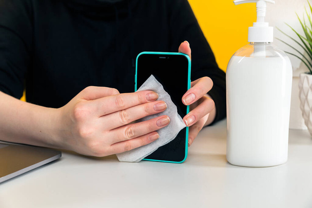 Desinfection concept. Woman desinfecting phone by wet wipe. - Photo, image