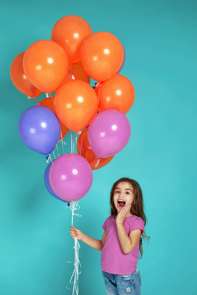 child girl in pink t-shirt posing with bright colorful air balloons - 写真・画像