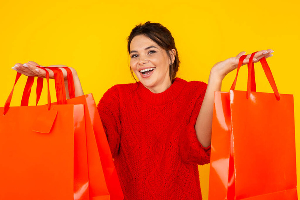 Nakupování online koncept. Šťastná žena s velkými taškami stojí izolované ve žlutém studiu. - Fotografie, Obrázek