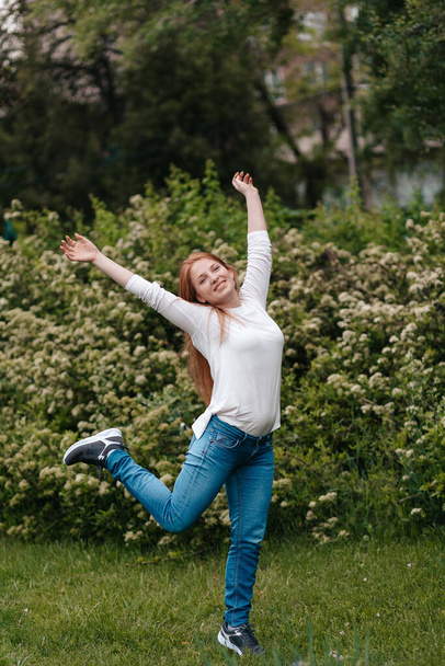 Happy and cheerful woman jumping on a green lawn - Fotó, kép