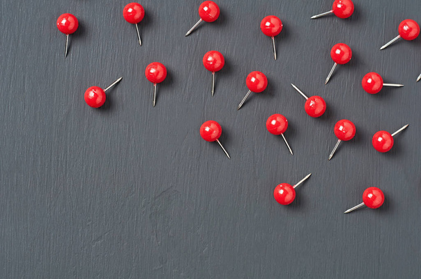 Scattered many red push pins on dark concrete desk in office, school or home. Space for text - Fotografie, Obrázek