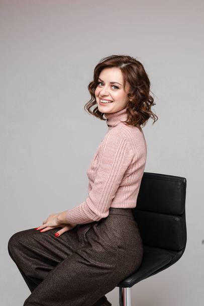 Schöne Frau sitzt auf einem Stuhl und lächelt, Bild isoliert auf weißem Hintergrund - Foto, Bild