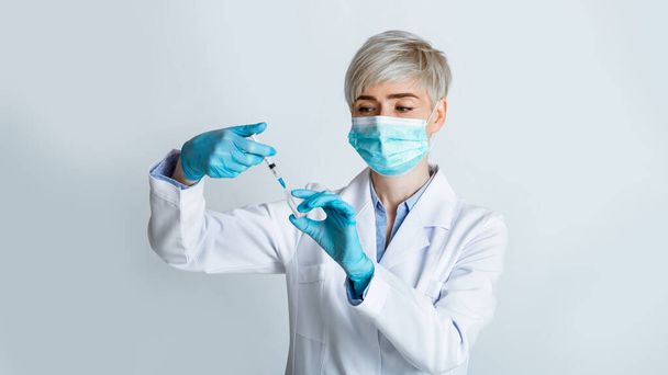 Ärztin in medizinischer Maske nimmt Spritze zur Spritze - Foto, Bild