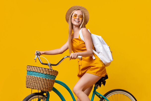 Nyári stílus. Tini lány visel kalap, napszemüveg és hátizsák lovaglás Vintage kerékpár - Fotó, kép