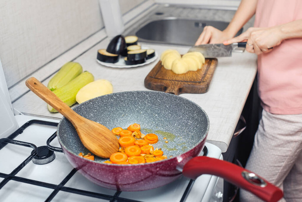 Roasting carrots in a deep wok pan. Frying for soup or cooking vegetable stew . - Fotoğraf, Görsel