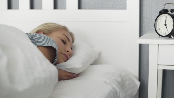 Young beautiful woman waked up by alarm clock in the morning - Filmmaterial, Video