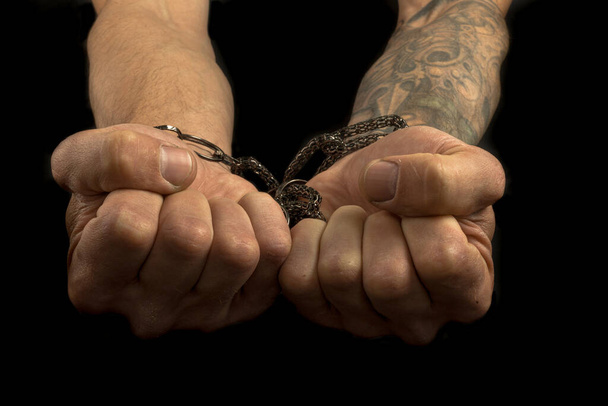 strong male working hands hold contrasting bright jewelry on a dark background. tattoos on the arms. hands tear jewelry - Photo, Image