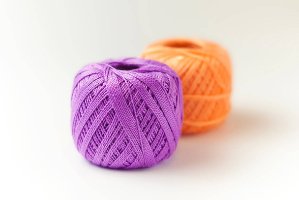 紫とオレンジの糸の2本の皮。白い背景に糸を編む。趣味. - 写真・画像