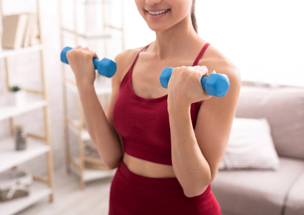 Unrecognizable young girl working out with weights, lifting dumbbells at home, closeup - Photo, Image