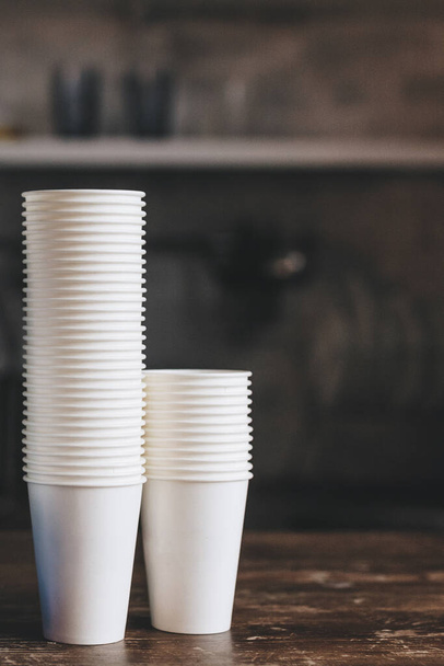 Pila de nuevas tazas de café para llevar en la mesa de madera en la cafetería
 - Foto, Imagen
