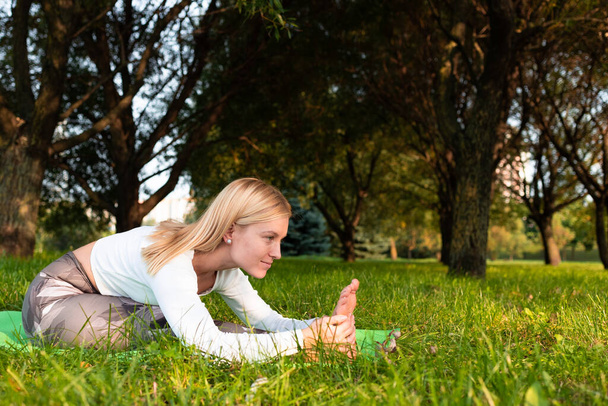 Sportos szőke jógázik a parkban - Fotó, kép