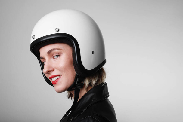 Close-up side portrait of happy biker young woman, wearing retro helmet, with red lips. Space for your text. - Foto, Imagen