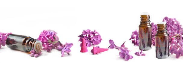 vista panoramica su bottiglia essenziale di olio e petali rosa di fiori lilla su sfondo bianco
 - Foto, immagini