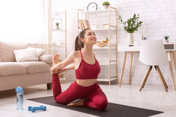 Quédate en casa, quédate bien. Muchacha milenaria atractiva dedicada a la práctica del yoga matutino en interiores
 - Foto, imagen
