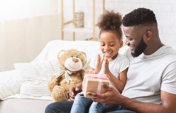 Excited black girl taking gift from daddy - Photo, Image