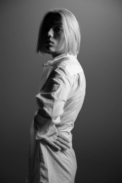 Fashion model. Young blond woman posing in studio wearing white shirt. Beautiful caucasian girl over gray background. Black and white - Foto, immagini