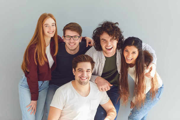Group of young people in casual clothes smiling while gray background. - Fotoğraf, Görsel