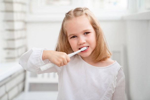 funny girl cleans teeth electric toothbrush - Foto, Bild