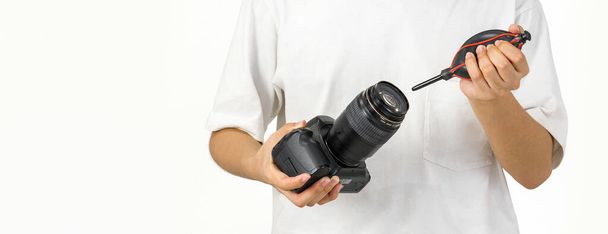 若い写真家は、空気送風機のカメラのクリーニングでカメラとレンズを掃除している. - 写真・画像