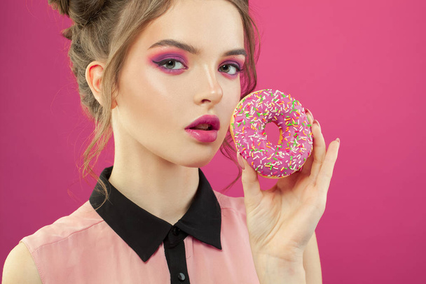 Retrato de moda de mujer hermosa sosteniendo donut sobre fondo rosa vivo
 - Foto, Imagen