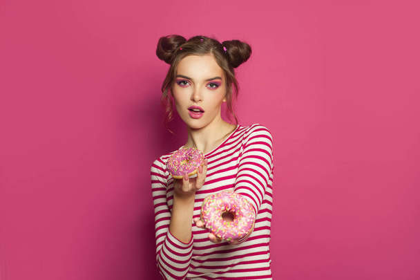 Fashion portret van leuke vrouw met donuts op kleurrijke roze achtergrond - Foto, afbeelding
