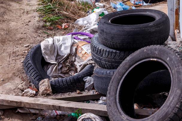 Old used car tires are in landfill in piles waiting for recycling. Car tires with garbage. Car wheel recycling - 写真・画像