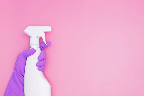 Female hand holding spray with detergent or sanitazer on pink background with copy space - Фото, зображення