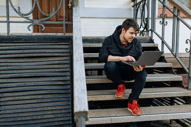 Молодий чоловік працює на своєму ноутбуці в центрі міста. Незалежна особа, яка вводить щось у свій документ. спілкування з друзями через Інтернет, веб-камера
 - Фото, зображення
