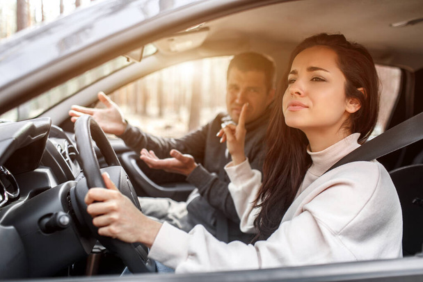 Pokyny k řízení. Mladá žena se naučí řídit auto. Její instruktor nebo přítel nemá rád, jak řídí auto. Ale ta holka je se sebou spokojená a toho chlapa neposlouchá.. - Fotografie, Obrázek