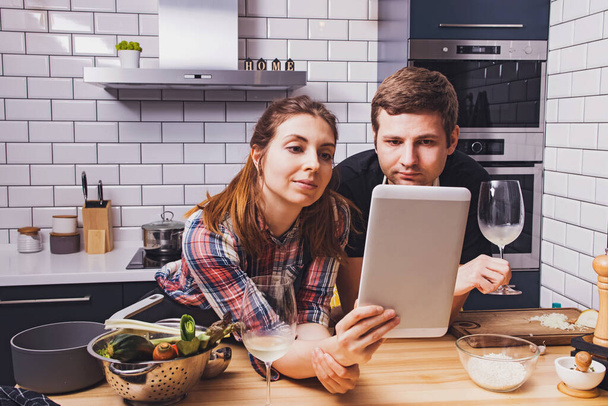 Young cheerful couple preparing food together at home - Valokuva, kuva