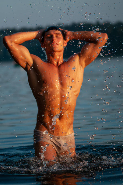 湖にポーズをとる筋肉質の男性モデル - 写真・画像