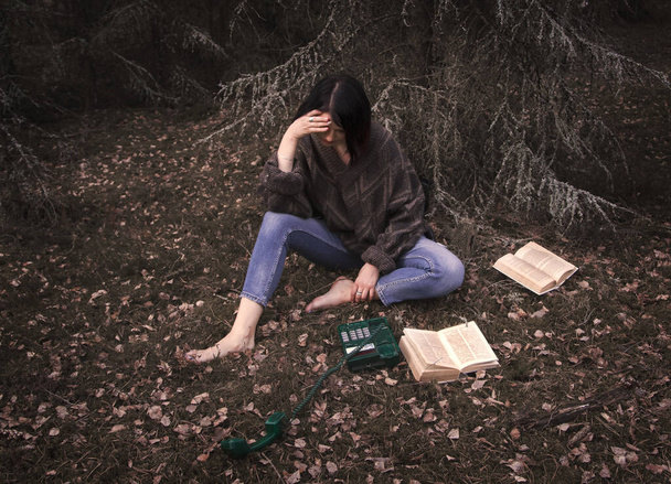 jonge vrouw is verdrietig met een handset in de natuur - Foto, afbeelding