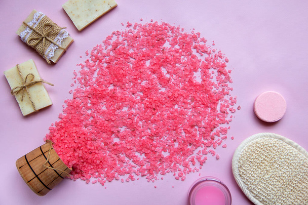 Bath salt poured into a circle, natural soap, shower sponge, bath bomb, cream on a pink background. The concept of relaxation and body care, organic bath products. Spa cosmetics. Flat lay. Copy space. - 写真・画像
