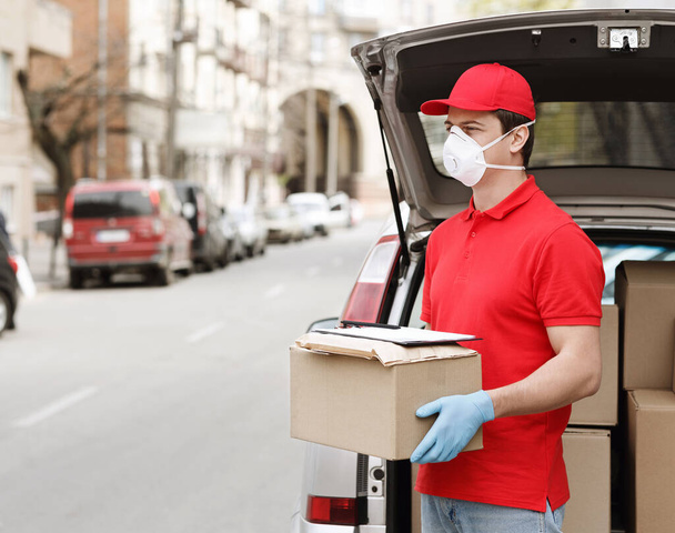 Protección del cliente contra el coronavirus en el momento de la entrega del paquete a casa. Mensajero cerca del maletero abierto del coche
. - Foto, imagen